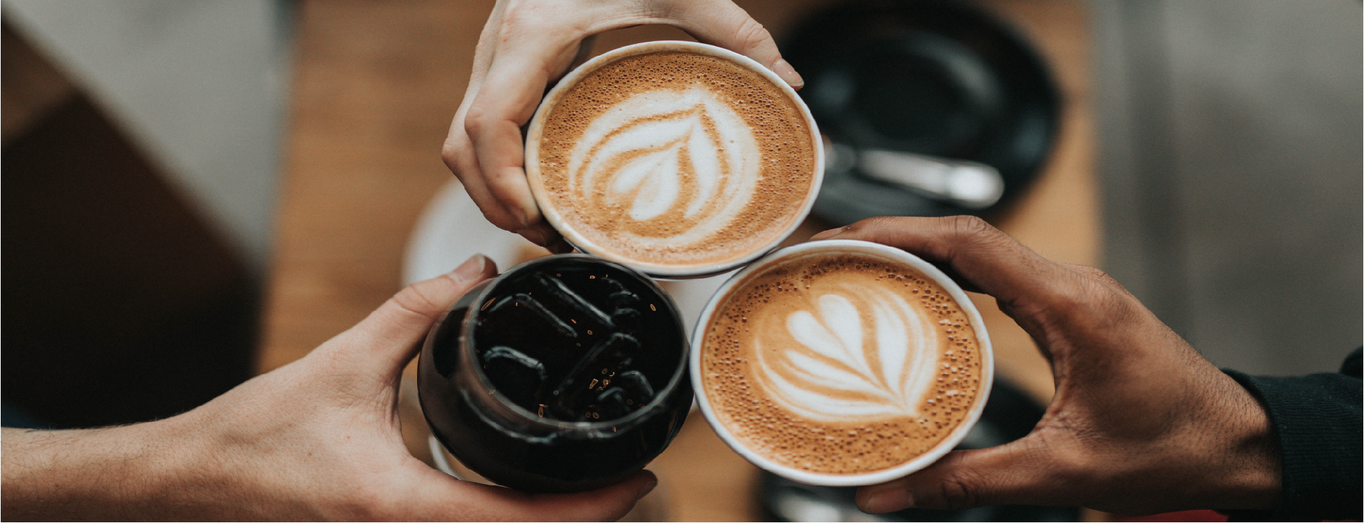 3 hands holding coffee cups