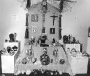 This is an ofrenda created in November 1997. This was set up in the Milwaukee Art Museum for Family Sundays. Jose Chavez lended the artwork. This ofrenda is in memory of my great-grandmother. A photograph of her and my great-grandfather is at the center. Some of her favorite things were placed on the ofrenda, complete with fried chicken and cornbread. Jose and I worked together to set this up. - Photo Credit: Joanne K. Peterson