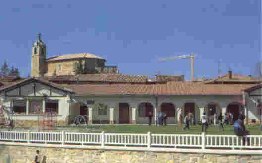 Las antiguas escuelas, los columpios y la iglesia al fondo