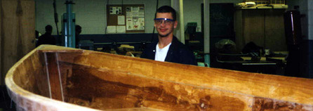 One student pauses in repairing a boat to smile for the camera.