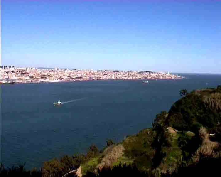 Near the statue of Christ in Lisbon, cruise boats look small.