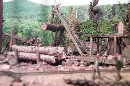 The A frame loader swings a log onto a pair of disconnected log cars