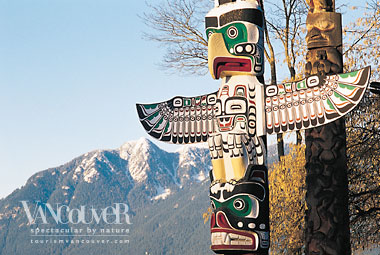 Totem poles with mountains in the background