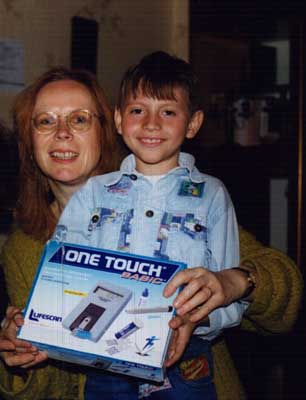 Renata giving a blood sugar meter to a diabetic child.