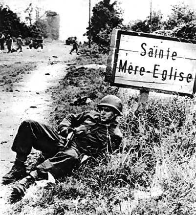 A US soldier takes a break near a road sign after the Allied forces took control of nearby town