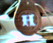 letter H, light blue on dark brown background