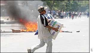 An East Timorese carries goods looted from shops in Dili, East Timor, 4 Dec. 2002. 