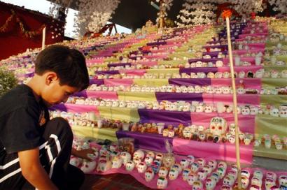 Alejandro Hernandez places candy skulls on a terraced slope where National Autonomous University of Mexico students collected more than 5,600 of the edible skulls, which are traditional offerings during Day of the Dead festivities in Mexico, constructing the the largest skull wall in Mexico, Sunday, Oct. 31, 2004. Mexicans honor the dead on Nov. 1, when the souls of dead children are believed to arrive, and on Nov. 2, when adults are believed to return. (AP Photo/Marco Ugarte)