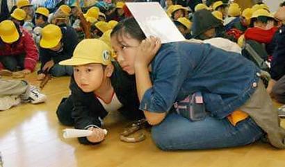 Japanese children crawl down on the floor at an elementary school in Kawaguchi town, northern Japan as a strong earthquake with a magnitude of 5.9 jolted the area November 8, 2004, the latest aftershock to hit a region struck by a deadly tremor last month. Photo by Kyodo/Reuters