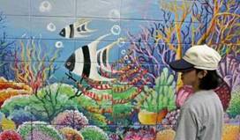 A high school student looks at a mural at the  U.S. Embassy in Bangkok April 21, 2005.  About 40 students gathered in front of the U.S. Embassy to transform walls into murals which reflect the Earth Day themes of coral reefs, wetlands and rain forests.      REUTERS/Sukree Sukplang