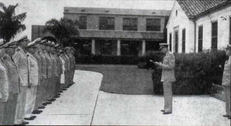 Standing in front of building 200, Rear Adm. J. P. Womble Jr., reads his orders detaching him from NTC.  Capt. E. A. Tarbutton is at the right.  The photo was taken from the July 23, 1948 issue of 'The Hoist.'