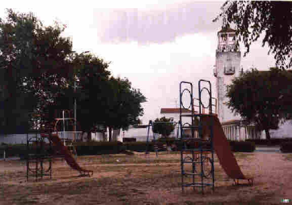 Parque Infantil de Novelda del Guadiana, con la Iglesia Santa Mar&iacute;a Magdalena al fondo.