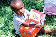 An evangelised child with shoebox and religious literature