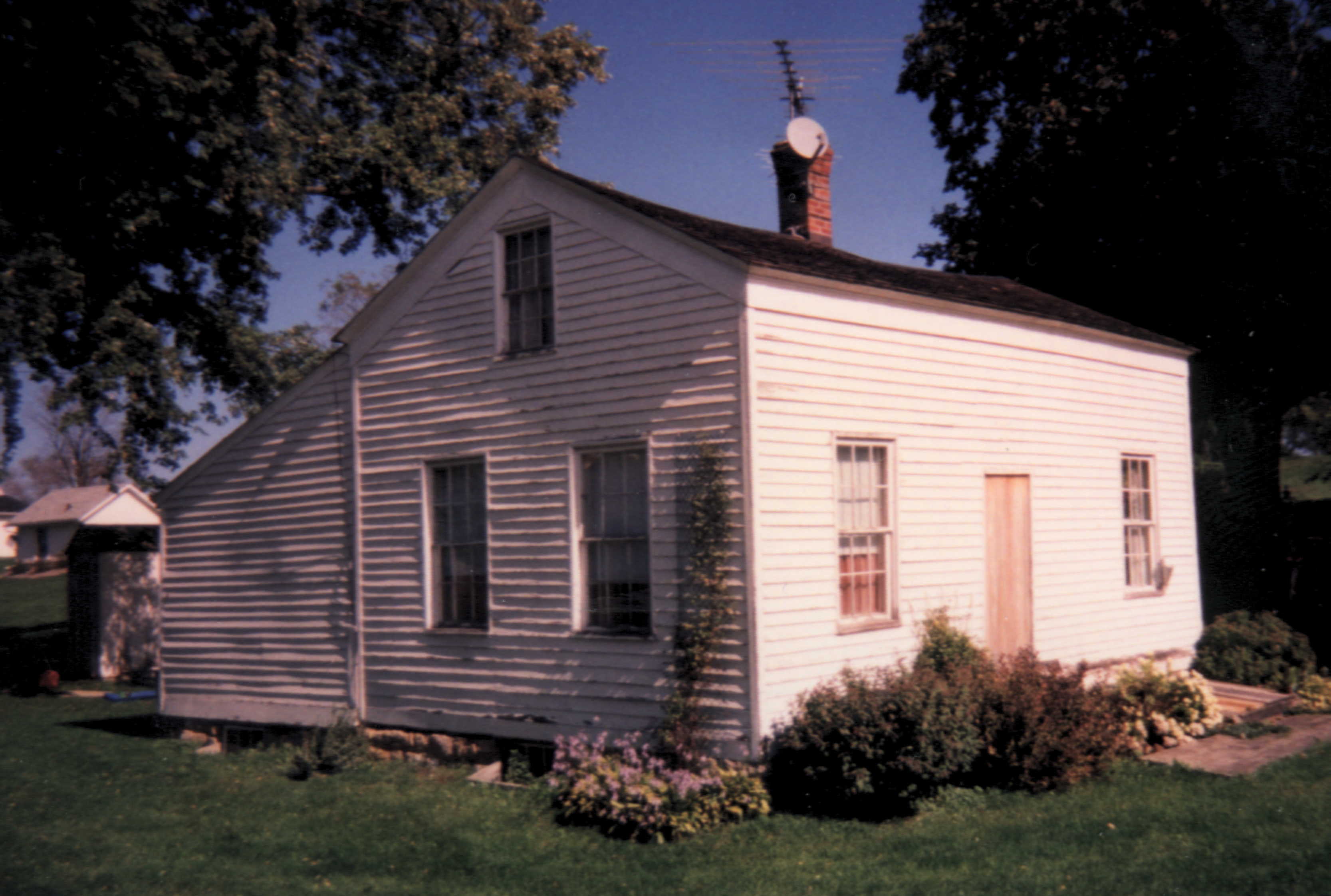 This building housed Wiota's first U. S. Post Office. 
The rear addition, which gives the dwelling a 'salt-box' appearance, was probably added later.
(Credit: Robert A. Braun.)