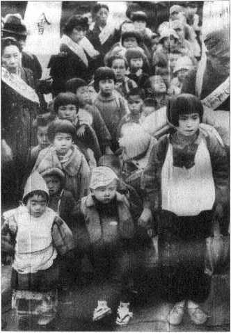 Watanabe Chizuko, aged seven, December, 1946. She is the girl in front with the white sash around her neck.
