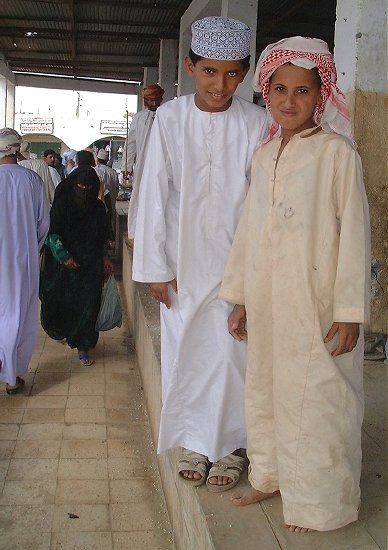 Two young Omani boys posing (and an Omani woman approaching).