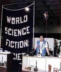 Gary Louie con su globo, al lado del antiqu�simo estandarte de la Sociedad Mundial de Ciencia Ficci�n. Sigue siendo el mismo que observ� recientemente en Torcon 3 - 2003.