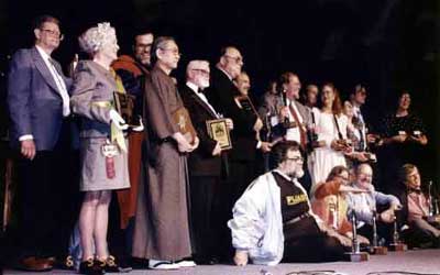 Ganadores de la noche: Poul Anderson, Marjii Ellers, Takumi Shibano, Andrew Porter, Ray Beam, Mike Resnick por Laura Resnick, Don Maitz (asomado debajo de la barbilla de Resnick), Gardner Dozois, Peggy Ranson, James Gurney (detr�s de Ranson), Nicki y Dick (Robert) Lynch, Connie Willis (con sus 2 hugos). Sentados: Harry Warner Jr., Janet Kagan (midiendo la altura de los Hugo), Vernor Vinge y  Martin Hoare por Dave Langford.