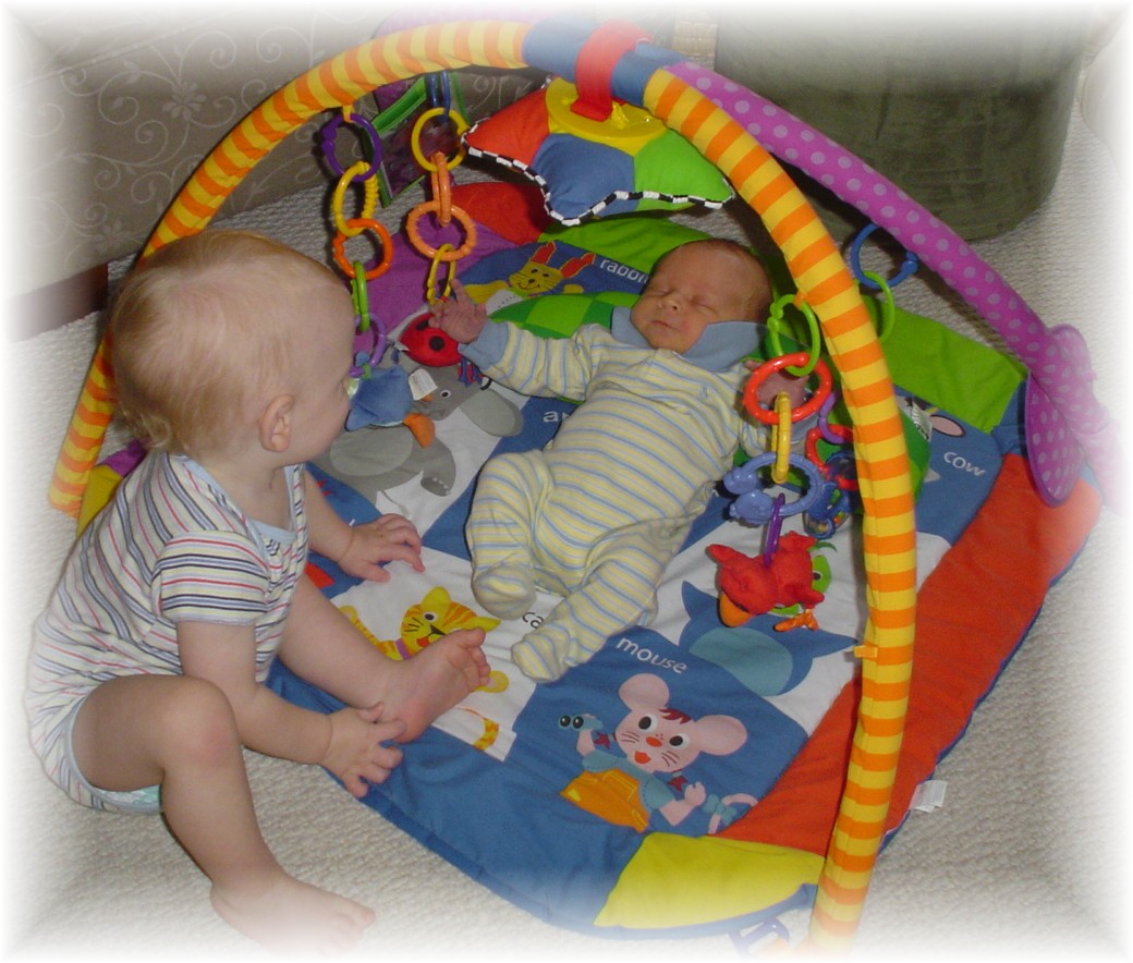 Aidan showing John Paul the toys in his play mat...