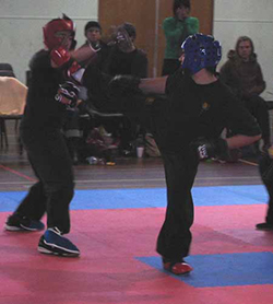 Ho (in red) blokes a side kick during point sparring bout.