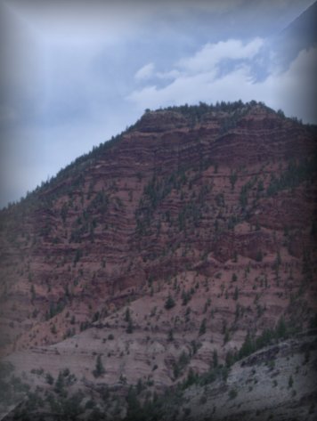 One of many red rock/greenery hills within the Rocky Mountains