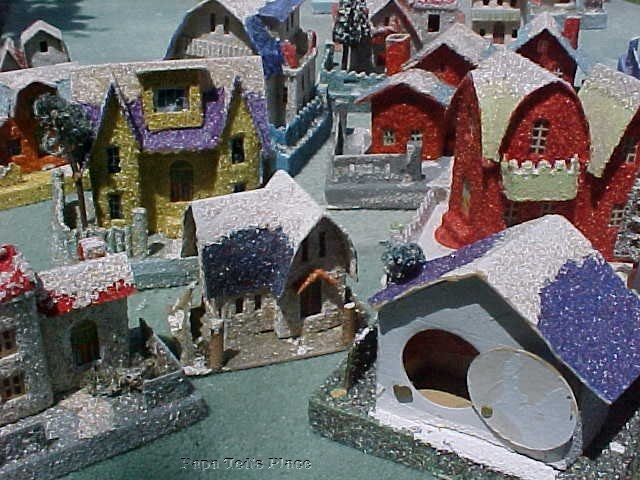 These are mostly full Cocos - in other words, 100% covered by the shredded cellophane floss. Fences,bases,walls and roof. More houses are found as partials; the whole building or very often just the roof in coco, for example. Other parts will be in flat or in sand stucco. One or two in the background can be seen with sand bases. The house in the foreground shows one of the harder-to-find pivoted "candy-filler" hatches on the back, the idea being that you could either illuminate it with a string of lights, or use it as a surprise box. 