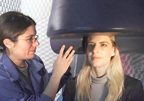 Una especialista ajusta el casco del magnetoencefalgrafo a una paciente