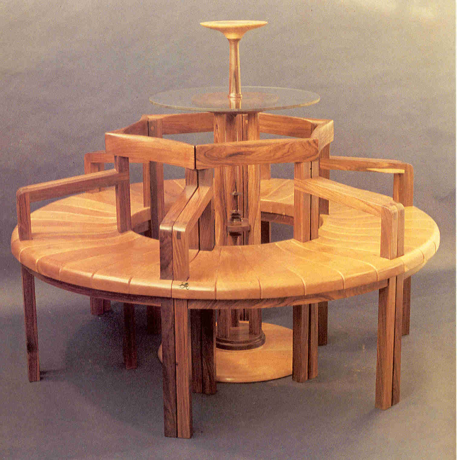 Circular bench/chairs with center pedestal table, pau ferro and cherry, 60"D x 42"H. Chairs can be arranged in various configurations.