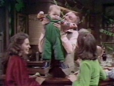Jill and Maeve look on as Johnny holds Edmund, 1978