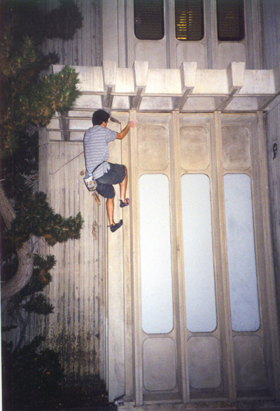 Stephen on the AP&M Corner problem.&nbsp; Getting over the roof requires an interesting heel hooking maneuver.&nbsp; Descent is by jumping into, then downclimbing, the tree on the left.