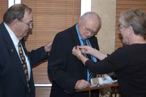 Saginaw Downtown Lion member and incoming District Governor Lion Bob Heft (left) awards Lion Secretary Wil Hufton with a very special award honoring him for his dedication to the Saginaw Downtown Lions Club.&nbsp; Hufton's wife, Jan, is seen placing a pin onto his lapel.