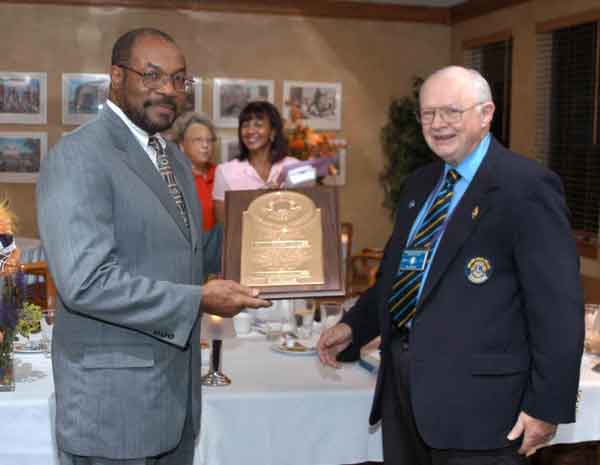 Outgoing president Lion JT Holmes, is awarded this Past President plaque from club secretary Lion Wil Hufton.
