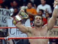 Malenko has his left arm raised by the referee and the other holding the Light Heavyweight title.