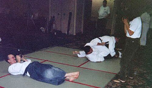Janet "The Shy" and Kim "The Non-Girl" take pictures of each other while grown men cuddle/wrestle in the background.
