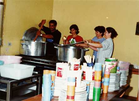 Volunt�rios preparam almo�o fornecido aos participantes de reuni�o p�blica dominical.