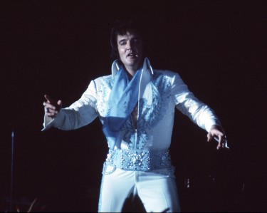 Elvis onstage in 1976 wearing a blue Phoenix jumpsuit and blue scarf