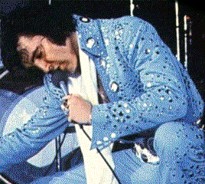 Elvis kneeling onstage.