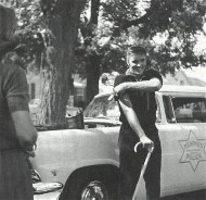 Elvis standing by a police car