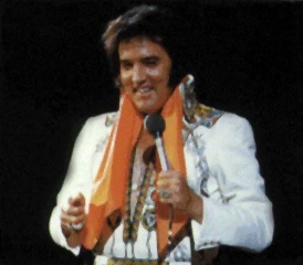 Elvis onstage wearing orange scarf.