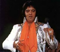 Up close shot of Elvis onstage wearing an orange scarf.