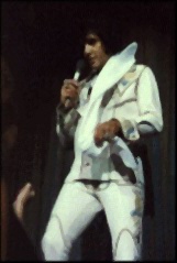 Elvis about to toss a scarf to a fan.