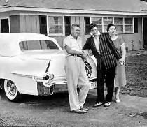 Elvis standing outside his house with his parents in 1955.