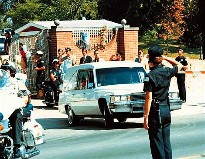 Officer outside Graceland salutes as the hearse goes by.