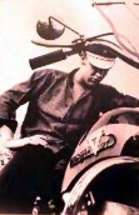A young Elvis stands by his motorcycle.