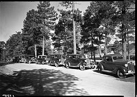 AUTO CARAVAN ON S RIM, GRCA. CARS ARE PARKED IN AN EAST-FACING ROW ALONG THE ROAD SOUTH OF THE RAILROAD TRACKS. CIRCA 1931 NPS PHOTO