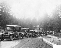 STRING OF FRED HARVEY TOURING CARS ON THE EL TOVAR HILL. PUBLIC GARAGE BEHIND. CIRCA 1921. FRED HARVEY CO.