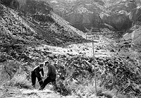 TRANS-CANYON TELEPHONE LINE CONSTRUCTION -  2 CCC ENROLLEES ADJUSTING TURNBUCKLE ON A GUY WIRE FROM A METAL POLE ON THE TONTO PLATFORM. THESE GALVANIZED IRON POLES WERE SET IN SAND & SULPHUR. CIRCA 1935 NPS PHOTO BY LAWS.<br><br>