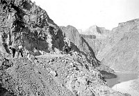 RIVER TRAIL CONSTRUCTION BY CCC ENROLLEES. MEN WORKING WITH PICKS ABOVE RIVER. CIRCA 1934. NPS. 