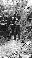 1928 KAIBAB BRIDGE CONSTRUCTION. WORKERS STANDING TOGETHER AND WEARING DUST MASKS. TUNNEL BEHIND THEM. GC 28 L27. 1928 NPS. 