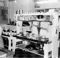 PHANTOM RANCH STAFF IN KITCHEN GARNISHING PLATES OF FOOD BEFORE SERVING TO GUESTS. 1967. ERVIN. NPS. 